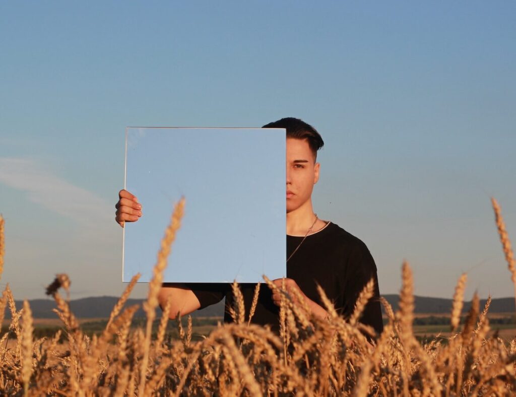 man in black crew neck shirt and black hat standing on brown wheat field during daytime